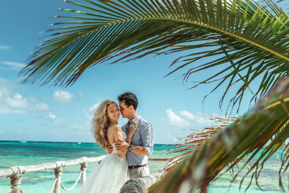 Медовый месяц время. Романтическое путешествие. Свадебная фотосессия на Мальдивах. Пара на пляже с пальмами. Влюбленные на берегу моря.